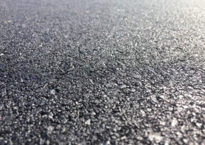 Close-up of asphalt texture on a road surface, capturing its rough and gritty appearance.